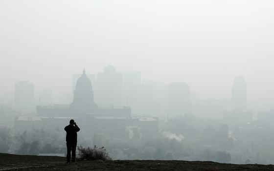 A man stops to take a picture of the Utah State Capitol and buildings that are shrouded in smog in downtown Salt Lake City Dec. 12, 2017. (CNS/Reuters/George Frey)