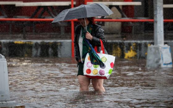 A woman walks through rain and flood waters in the Brooklyn borough of New York City Sept. 29, 2023, as the remnants of Tropical Storm Ophelia brought flooding across the mid-Atlantic and Northeast. Up to 5 inches of rain fell in some areas overnight, and as much as 7 inches more was expected throughout the day, New York Gov. Kathy Hochu said. (OSV News/Brendan McDermid, Reuters)