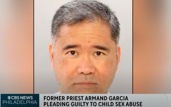 A brown man with graying black hair looks at the camera. A chiron at the bottom of the screen reads CBS News Philadelphia -- Former Priest Armand Garcia Pleading Guilty to Child Sex Abuse