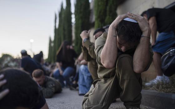 At a cemetery in Holon, central Israel, Oct. 26, Israelis take cover as a siren warns of incoming rockets fired from the Gaza Strip, during the funeral of Israeli man Sagiv Ben Svi, killed by Hamas militants while attending a music festival on Oct. 7. (AP/Petros Giannakouris)