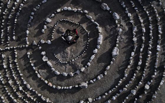 A group of Brazilian tourists hold hands standing in a circle at the heart of a stone labyrinth in the Pueblo Encanto spiritual theme park in Capilla del Monte, Argentina, July 19. (AP/Natacha Pisarenko)