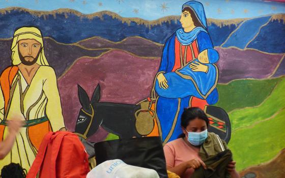 A woman gathers her belongings in front of a mural of Joseph and Mary at the CAFEMIN migrant shelter in Mexico City, Aug. 24. Sr. María Soledad Morales Ríos, one of the Josephine sisters whose congregation operates the shelter, said their charism is to care for the poor, including migrants, the way Joseph and Mary cared for Jesus. (GSR photo/Rhina Guidos) 