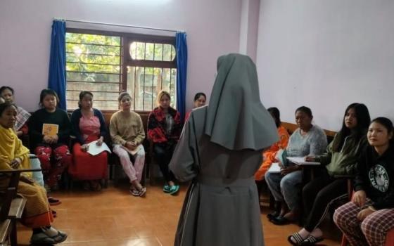 Nun, with back to camera, talks to a group of people. 