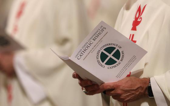 A bishop holds a booklet as he attends Mass in a file photo taken during the 2021 fall general assembly of the U.S. Conference of Catholic Bishops. (CNS/Bob Roller) 