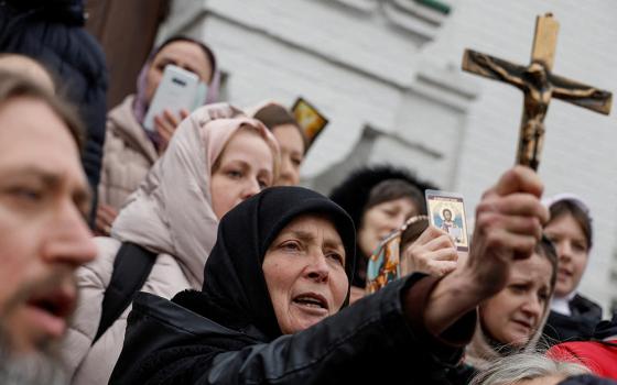 A woman holds a crucifix as others pray while blocking an entrance to a church compound in Kyiv, Ukraine, March 31 amid the Russian invasion. At the U.S. Institute of Peace in Washington Oct. 30, a panel of Ukrainian religious leaders discussed their role in responding to Russia's invasion. (OSV News/Reuters/Valentyn Ogirenko)