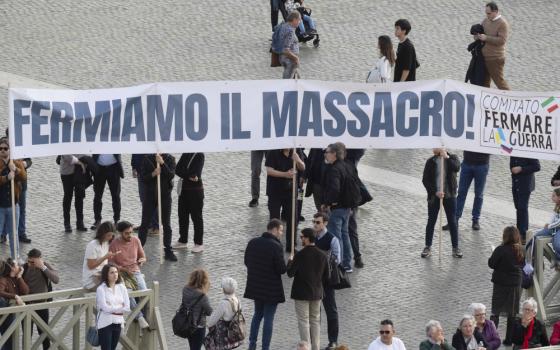 A group of people hold a long banner that says "Fermiamo il massacro" and "Comitato Fermare La Guerra"