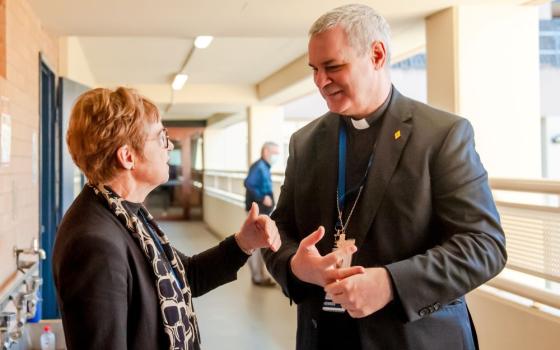 Bishop talks with a woman outside a meeting. 