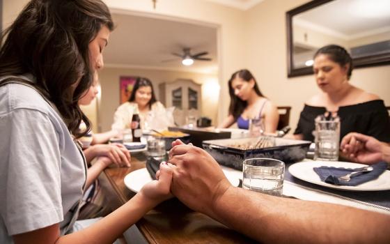A family prays around the dinner table. At higher rates than other groups studied in a new Pew survey, Catholics said that "being connected with loved ones who've passed" and "continuing family traditions" were essential to what being spiritual means to them. (OSV/Courtesy of Detroit Archdiocese)