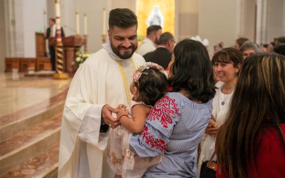 Father Luis Garcia is seen greeting a parishioner and her toddler in Houston June 4, 2022. (OSV News photo/James Ramos, Texas Catholic Herald)