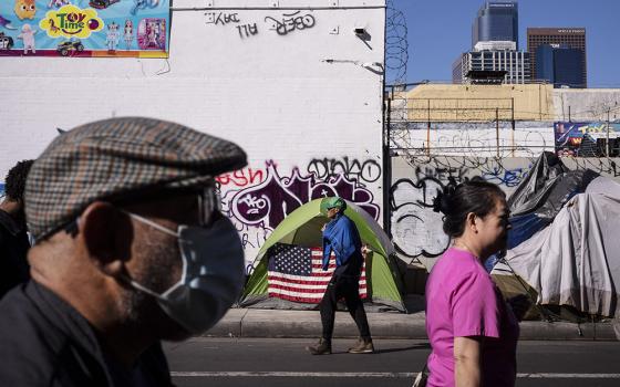 Pedestrians pass by a homeless tent adorned with an American flag across the street from the Los Angeles Mission in the Skid Row area of downtown Los Angeles Nov. 22, 2023. (AP/Jae C. Hong)