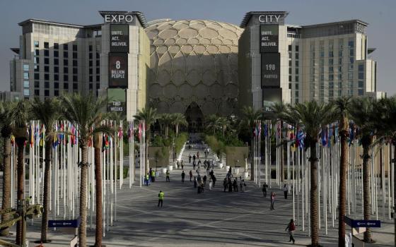 People walk through the venue for the COP28 U.N. Climate Summit, with the Al Wasl Dome in the background, at Expo City, Nov. 29, 2023, in Dubai, United Arab Emirates. (AP/Joshua A. Bickel)