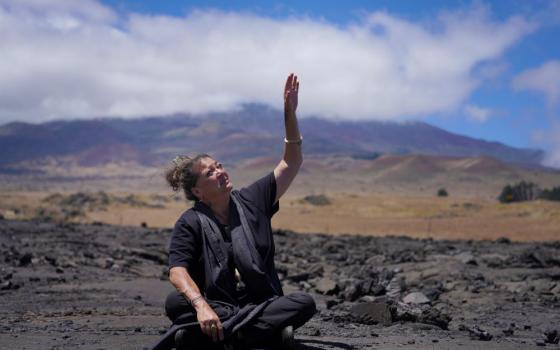 Kealoha Pisciotta, a cultural practitioner and longtime activist, sits on lava rock part of the way up Mauna Kea while giving an interview on the Big Island of Hawaii, on Saturday, July 15, 2023. Over the last 50 years, astronomers have mounted 13 giant astronomical observatories on Mauna Kea's summit. In 2019, Native Hawaiians including Piscioitta staged a year-long protest over construction of an additional telescope. (AP/Jessie Wardarski)