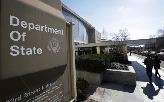A sign saying "Department of State" is visible outside of a brown-gray building