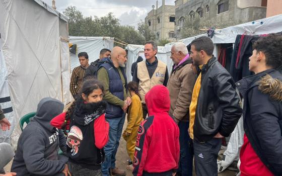 Sean Callahan, president of Caritas North America and CEO of Catholic Relief Services, in a tan vest, is pictured at a camp for displaced people during his visit to southern Gaza Jan. 23, 2024. (OSV News photo/courtesy Catholic Relief Services)