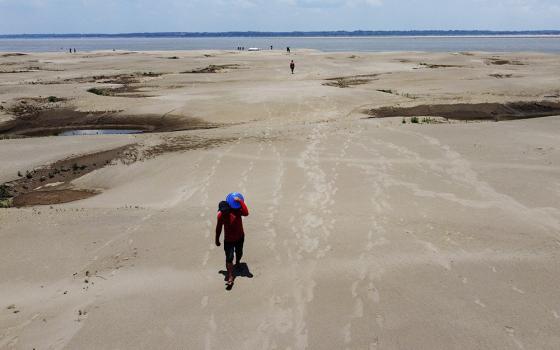 Residents of a riverside community carry food and containers of drinking water from an aid distribution due to the ongoing drought in Careiro da Varzea, Amazonas state, Brazil, Oct. 24, 2023. Earth last year shattered global annual heat records, numerous scientific bodies reported in early 2024. (AP/Edmar Barros, File)