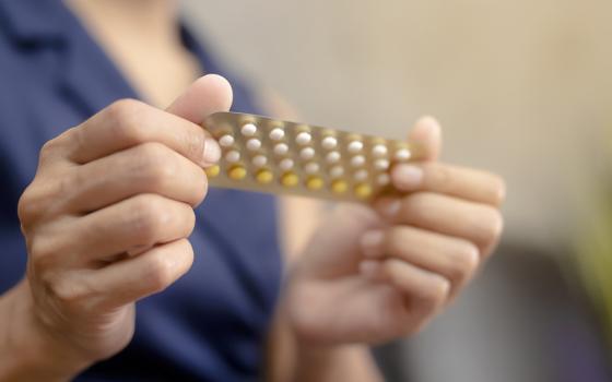 Woman holding a blister pack of birth control pills (Dreamstime/Patcharin Simalhek)