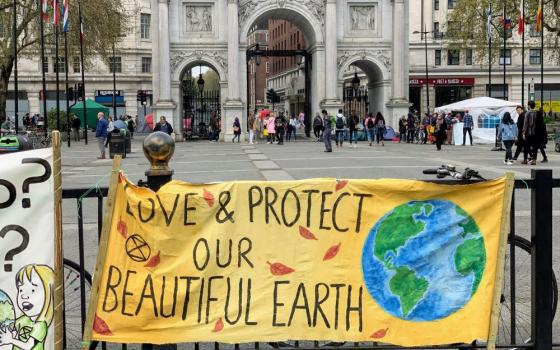 banner hangs on fence: "Love and protect our beautiful earth"