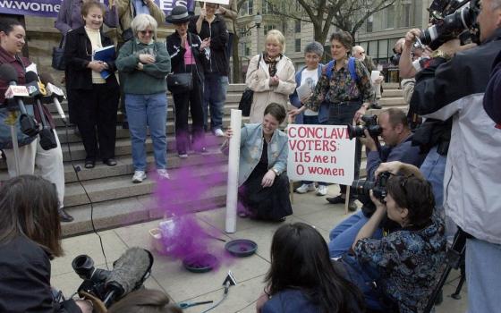 Anne Pezillo of the Women's Ordination Conference sends up "pink smoke" on the steps of Chicago's Holy Name Cathedral April 18, 2005, during a news conference protesting the exclusion of women from the conclave at the Vatican. The next day, cardinal electors chose Cardinal Joseph Ratzinger as pope.