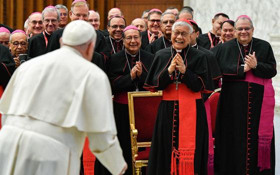Pope Francis is received with smiles and applause by Cardinal Lazarus You Heung-sik, prefect of the Dicastery for the Clergy, and a group of bishops participating in an international conference on the ongoing formation of priests in the Paul VI Audience Hall at the Vatican Feb. 8, 2024. (CNS/Vatican Media)