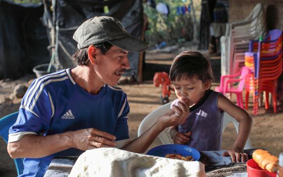 Farmer Santos Sorto feeds his son, Caleb, in La Caída, El Salvador. The family participates in a Catholic Relief Services program, which aims to mitigate the impact of COVID-19 pandemic and losses due to climate change. (OSV News photo/Oscar Leiva, Silverlight, Catholic Relief Services)