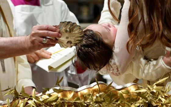 Pope Francis baptizes one of 13 babies during a Mass celebrating the feast of the Baptism of the Lord in the Sistine Chapel at the Vatican Jan. 8, 2023. 
