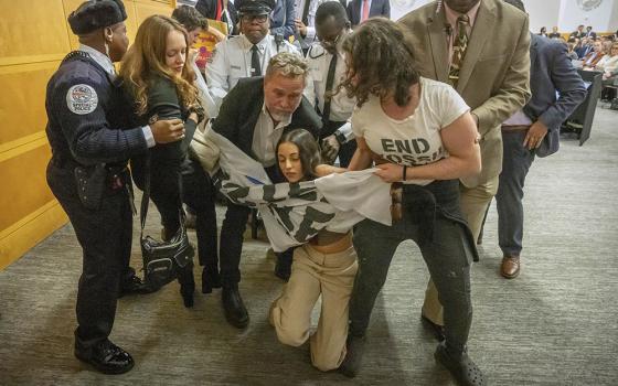 Climate protesters are removed after interrupting a speech by Federal Reserve Chairman Jerome Powell at the 24th Jacques Polak Research Conference at the International Monetary Fund on Nov. 9, 2023, in Washington, D.C. (AP/Mark Schiefelbein)