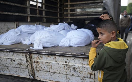 A Palestinian boy stands by the bodies of relatives killed in the Israeli bombardments of the Gaza Strip in front of the morgue of the Al Aqsa Hospital in Deir al Balah Feb. 24. (AP/Adel Hana)
