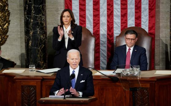 President Biden delivers State of the Union address on March 7, 2024. Behind him, Vice President Kamala Harris stands applauding, and Speaker of the House Mike Johnson sits listening. 