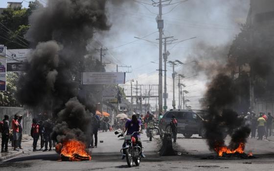 Motorists pass a burning barricade in Port-au-Prince