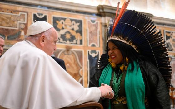 Pope Francis shakes hands with indigenous woman wearing head dress