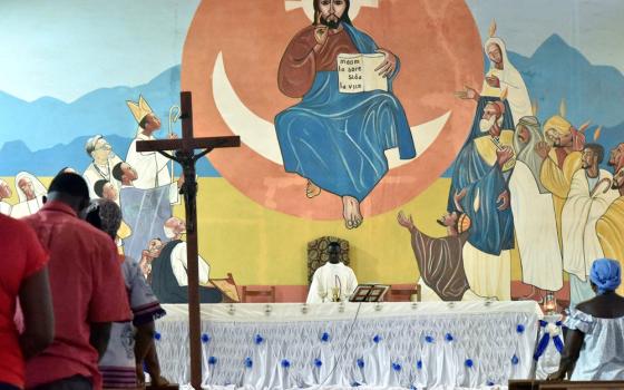 Worshippers in Burkina Faso church with vibrant mural behind altar