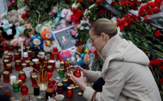 Woman lights candle at makeshift memorial