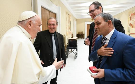 Pope Francis talks with two men. 