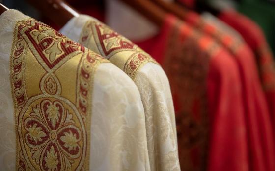 Clerical vestments hang on rack.