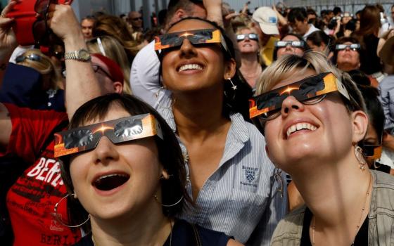 People wearing protective eyewear stare up at sky