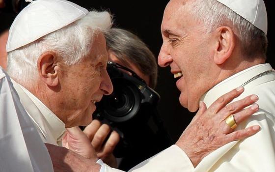 Pope Francis greets retired Pope Benedict XVI during an encounter for the elderly in St. Peter's Square at the Vatican Sept. 28, 2014. 