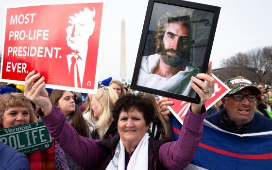 A woman holds an image of Jesus and a poster about President Donald J. Trump during the annual March for Life rally in Washington Jan. 24, 2020. 