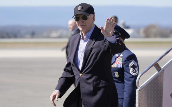 President Biden waves as he departs presidential plane. 