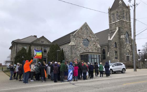 Protestors assemble outside stone church with pride flags