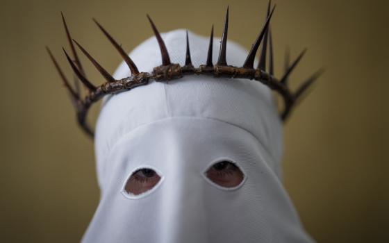 Spanish member of penitential order wears hooded regalia and crown of thorns.