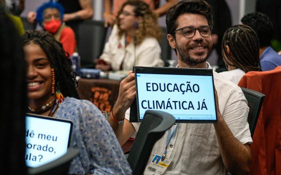 A man displays a sign that reads, "Climate education now," on Nov. 17, 2022, at the COP27 U.N. Climate Summit  in Sharm el-Sheikh, Egypt. (AP/Peter Dejong)