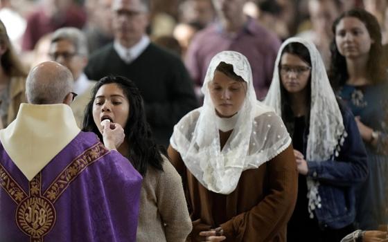 People receive communion during Catholic Mass at Benedictine College Dec. 3, 2023, in Atchison, Kansas. Many students, many of whom grew up in conservative Catholic families, jokingly call it “the Benedictine bubble.” And it might be a window into the future of the Catholic Church in America. (AP/Charlie Riedel)