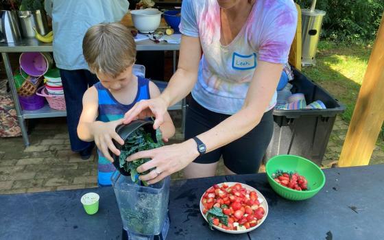 Grow It organizer Leah Reichardt-Osterkatz, right, helps children make smoothies from strawberries they picked, plus kale grown on the farm, at Spring Forest in Hillsborough, North Carolina, on Wednesday, May 29, 2024. (RNS photo/Yonat Shimron)