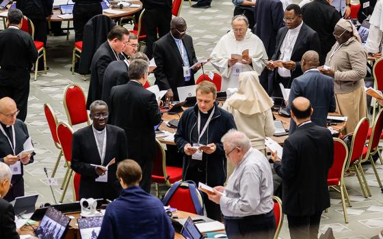 Members of the assembly of the Synod of Bishops pray before a working session in the Vatican's Paul VI Audience Hall Oct. 26, 2023. (CNS/Lola Gomez)