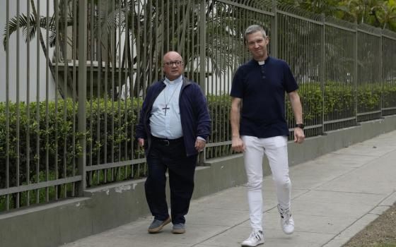 Bertomeu and Scicluna walk down sidewalk, wearing street clothes and collars. 