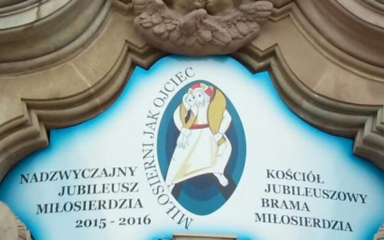 Logo with text and icon framed by stone carving. 