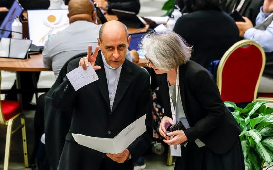 Cardinal Víctor Manuel Fernández, prefect of the Dicastery for the Doctrine of the Faith, speaks with Xavière Missionary Sr. Nathalie Becquart, undersecretary of the Synod of Bishops, before the start of a morning session of the synod in the Paul VI Audience Hall at the Vatican Oct. 21. (CNS/Lola Gomez)
