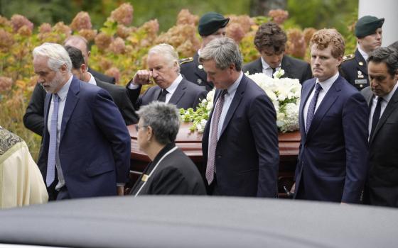 The men walk carrying casket.