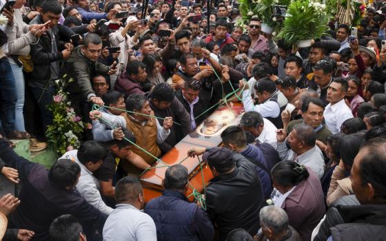 Enormous crowd --- dozens deep --- swarms around coffin as it descends.