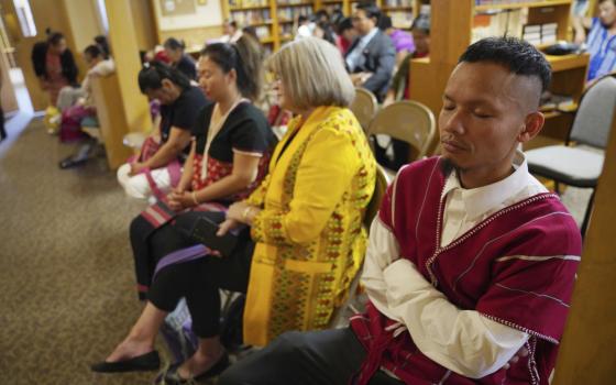 People seated in rows, eyes closed. 